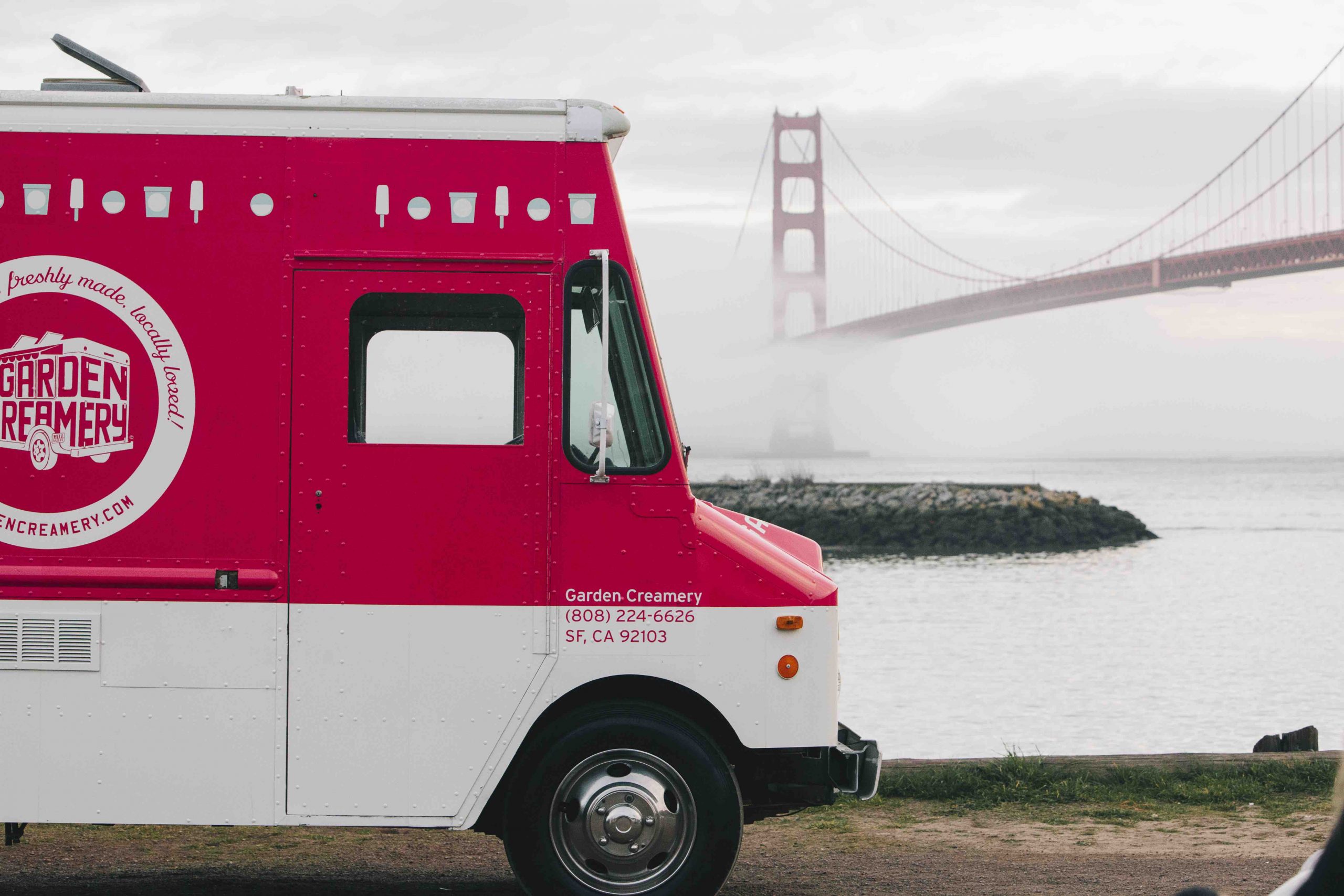 A red and white food truck in front of the San Francisco Bay Bridge