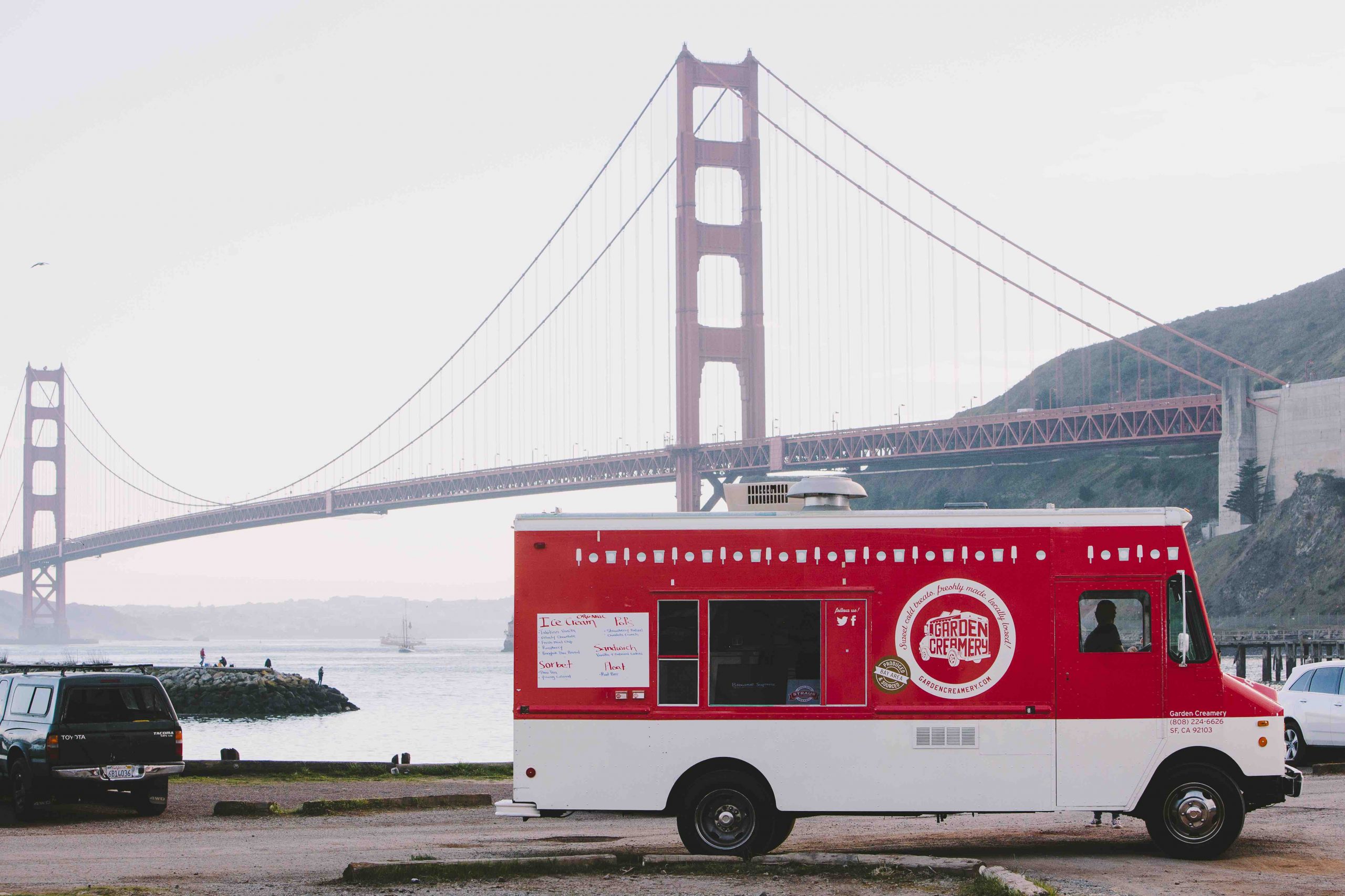 Red and white food truck in front of a red bridge