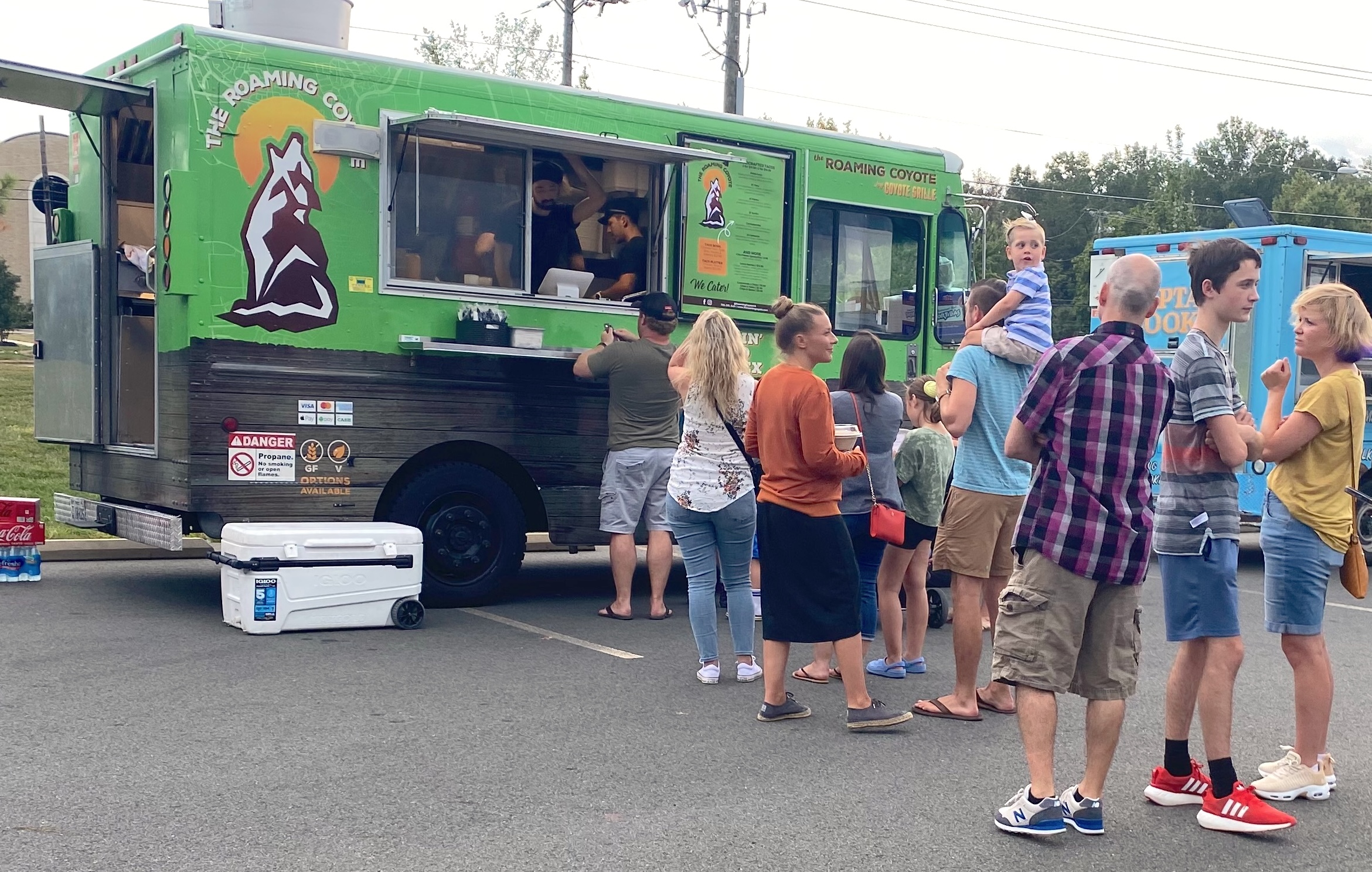 Green Roaming Coyote food truck with a line of customers