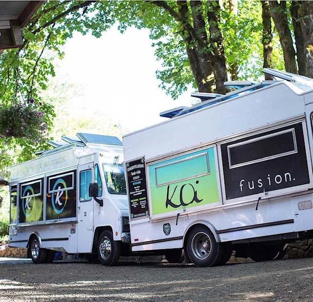 Two white food trucks parked in a green park